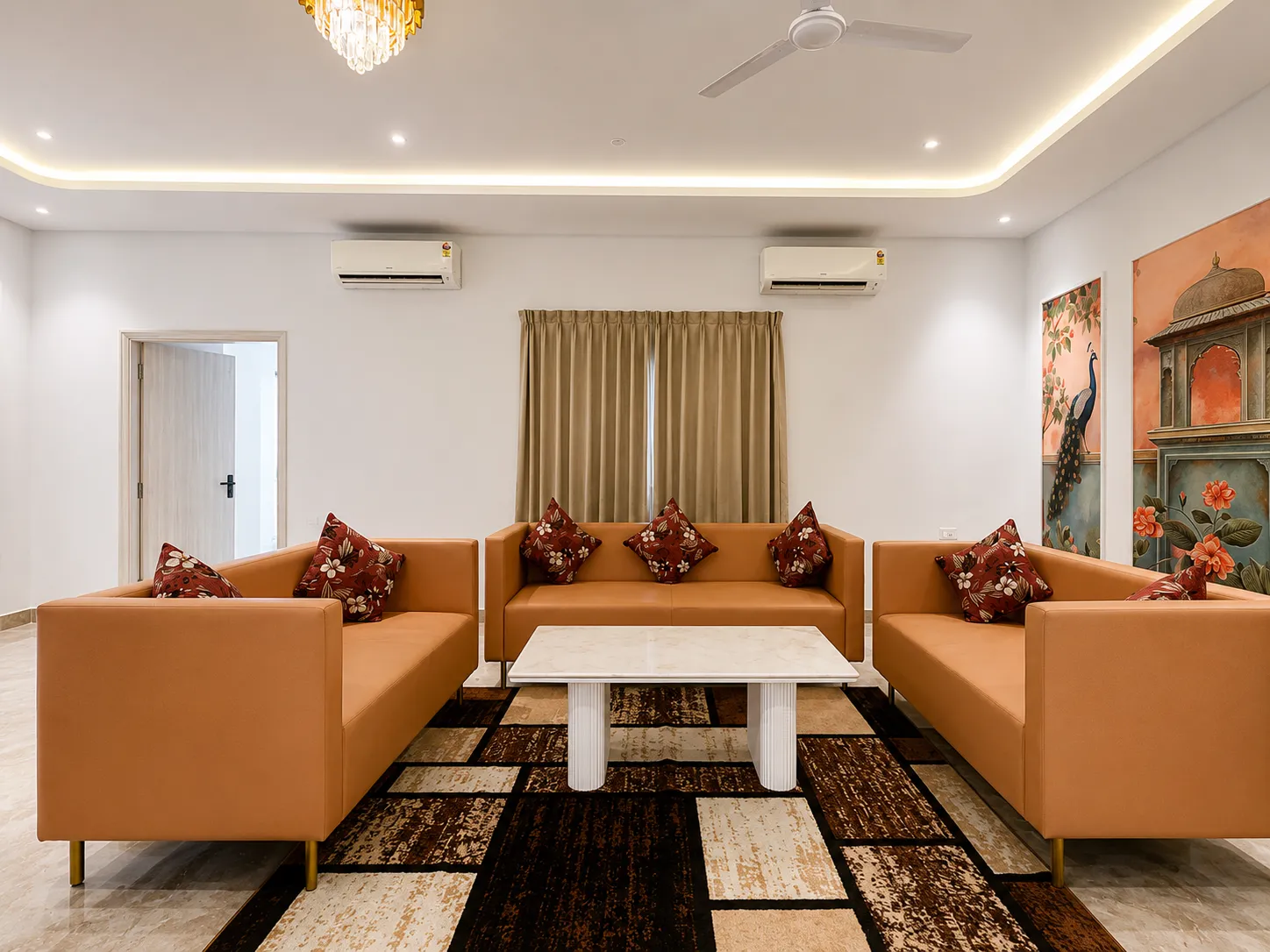Tan sofas gathered under warm chandelier light