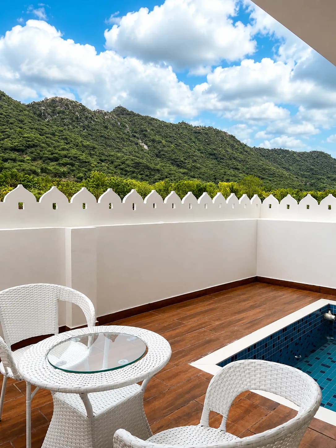Private terrace plunge pool with crenellated white parapet and hill views