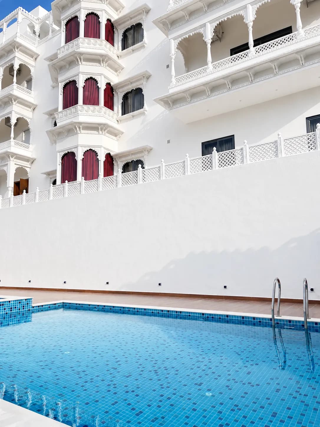 Carved jharokha balconies rising above the pool