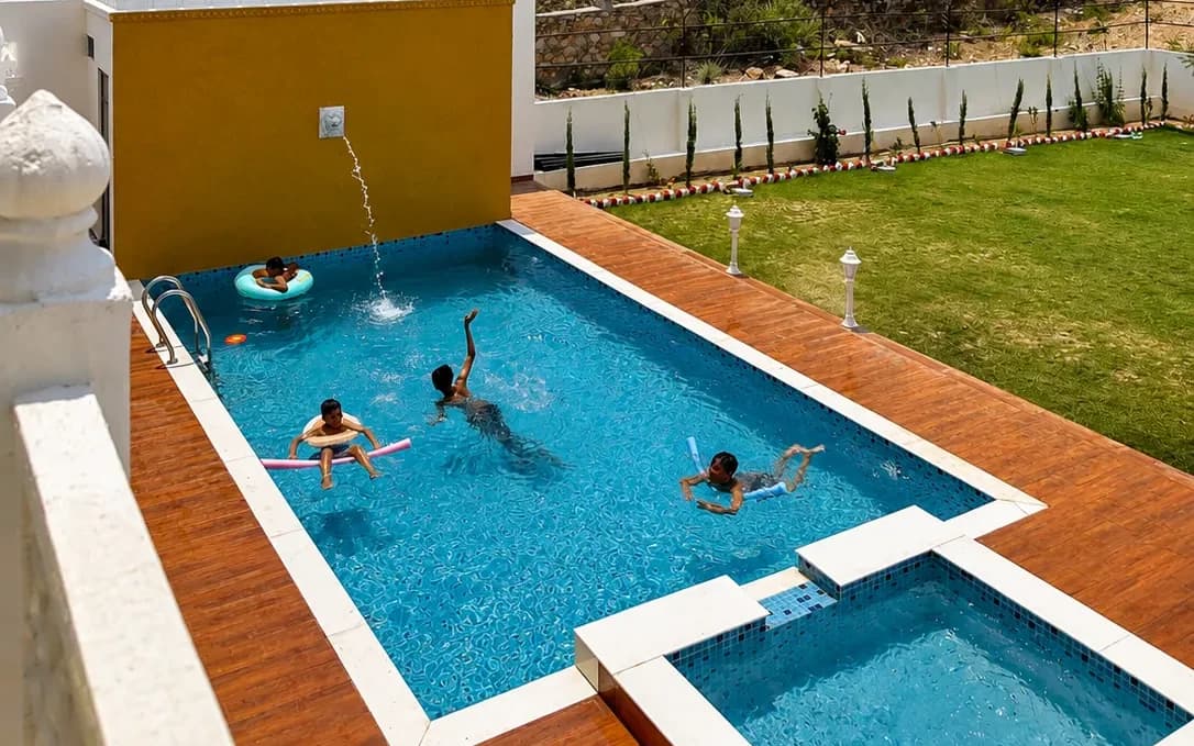Children splashing and swimming in the villa's garden pool beside the lawn