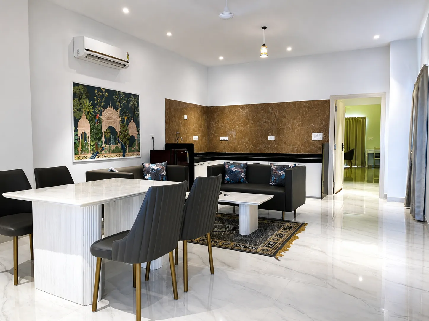 First-floor lounge with charcoal sofas, marble dining table, and crimson jharokha window seat