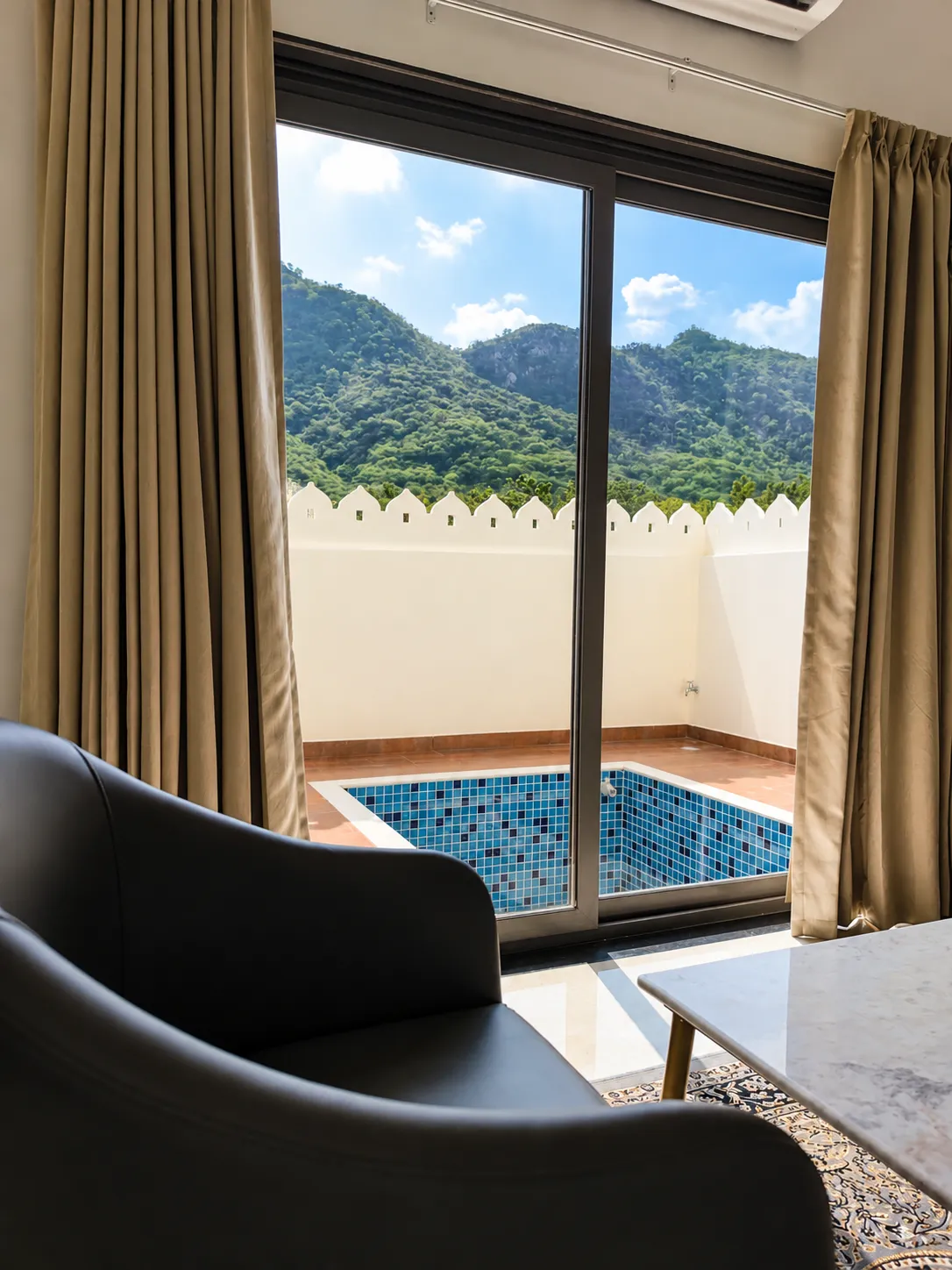 Sitting area opening onto a private plunge pool terrace with Aravalli views