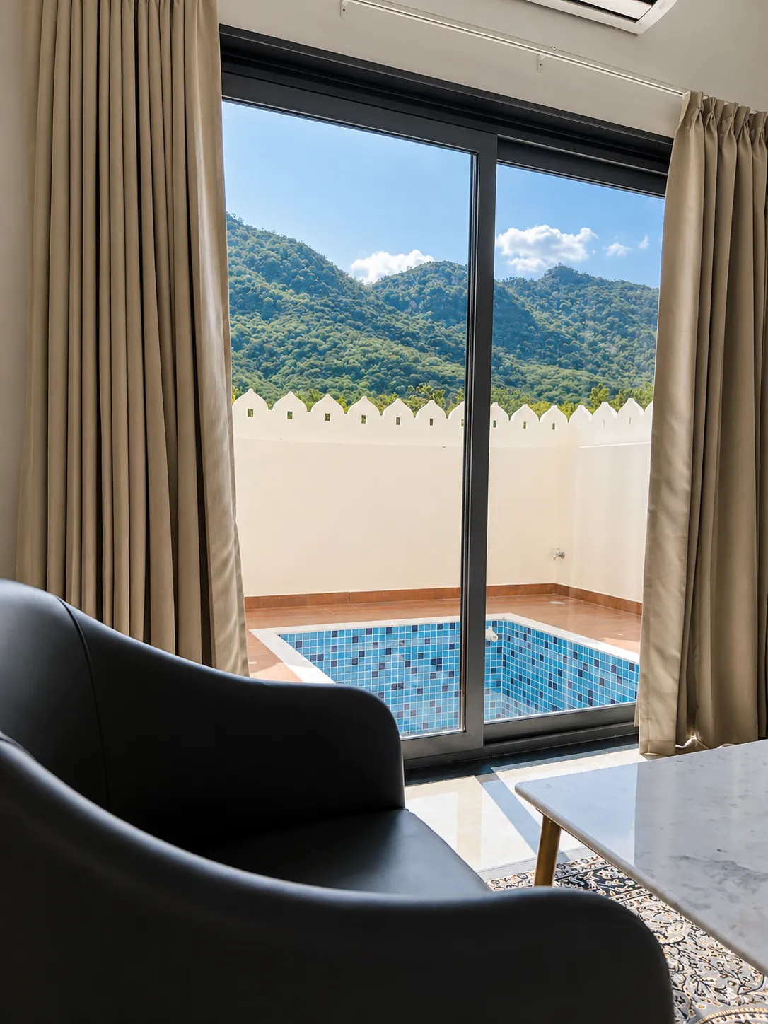 Suite sitting area with sliding doors framing a private plunge pool and the hills