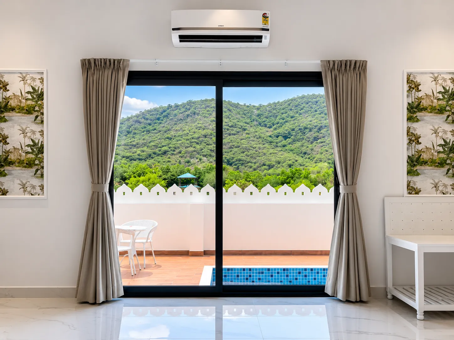 Sliding glass doors framing a private plunge pool, crenellated parapet, and the Aravalli Hills